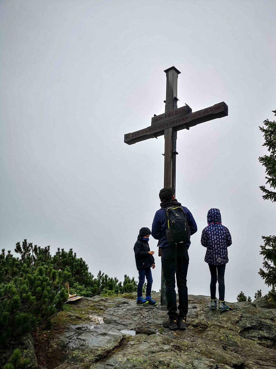 Kinder am Gipfelkreuz in Österreich während einer Familienreise