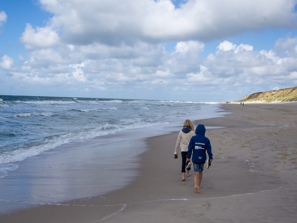 Kinder spazieren am Strand während des familienurlaubs in deutschland mit kindern