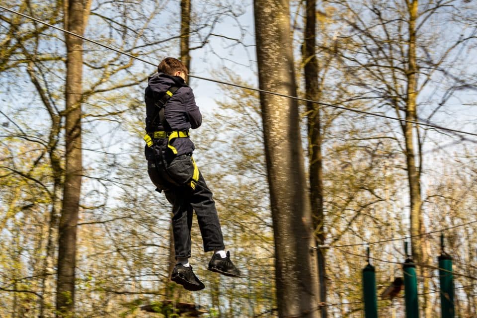 Kind fährt mit einer Seilrutsche durch den Wald