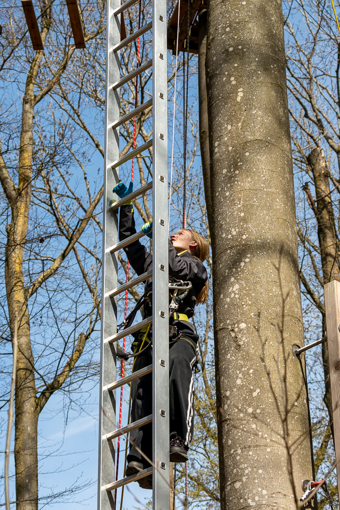 Teenager steigt eine Leiter im Hochseilgarten hinauf