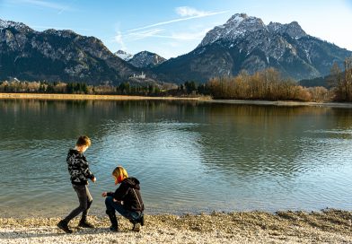 Kinder am See mit Blick auf Schloss Neuschwanstein und Bergpanorama beim Kurzurlaub Deutschland mit Kindern