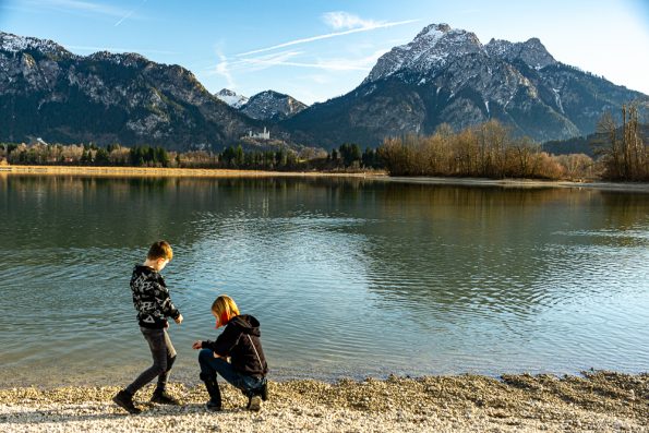 Kinder am See mit Blick auf Schloss Neuschwanstein und Bergpanorama beim Kurzurlaub Deutschland mit Kindern