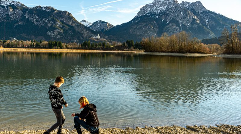 Kinder am See mit Blick auf Schloss Neuschwanstein und Bergpanorama beim Kurzurlaub Deutschland mit Kindern