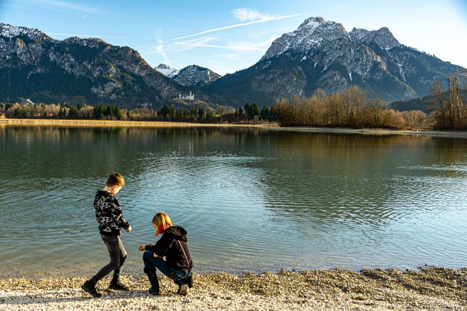 Kinder am See mit Blick auf Schloss Neuschwanstein und Bergpanorama beim Kurzurlaub Deutschland mit Kindern