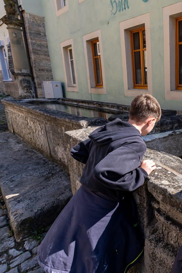 Kind schaut in einen Brunnen in der Altstadt von Rothenburg