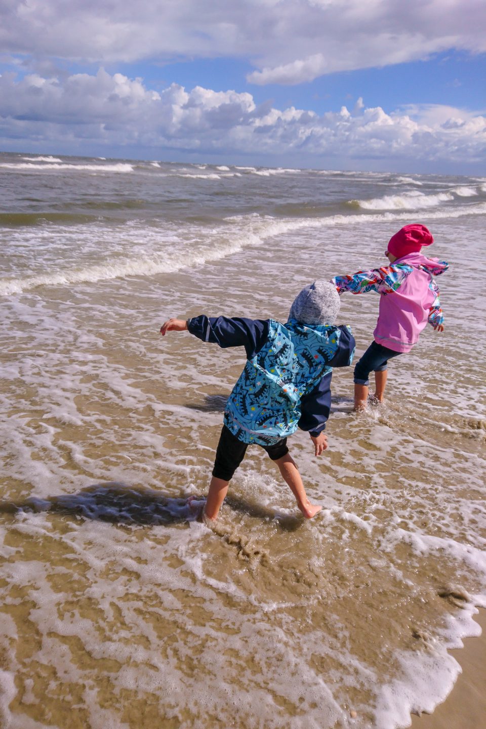 Kinder spielen in den Wellen beim Kurzurlaub auf Spiekeroog an der Nordsee