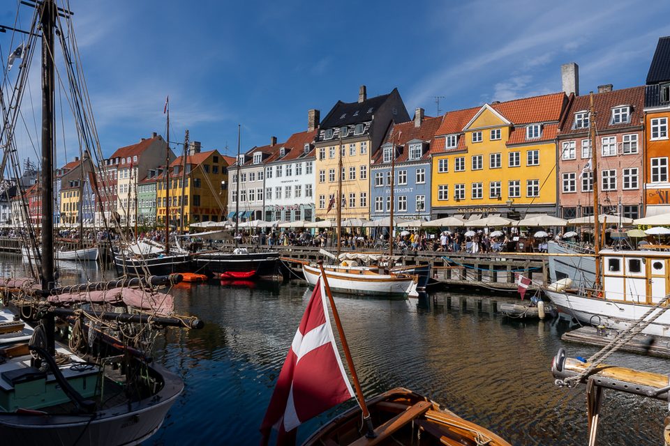 Historische Schiffe und bunte Häuser in Nyhavn mit dänischer Flagge
