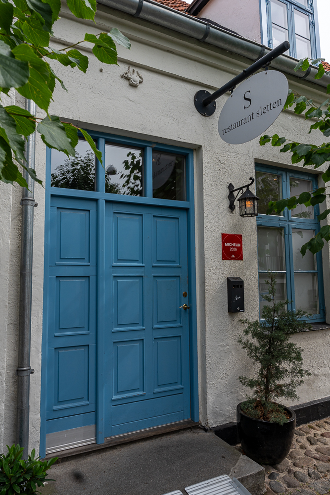 Eingang des Restaurant Sletten mit blauer Tür und Michelin-Plakette