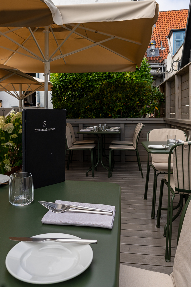 Terrasse des Restaurant Sletten mit gedeckten Tischen und Sonnenschirmen